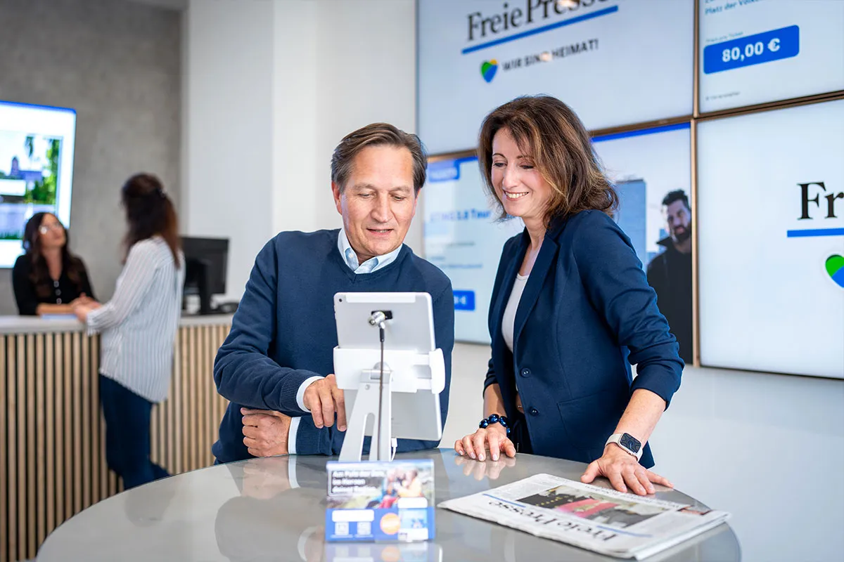Zwei Mitarbeitende der Freien Presse am Empfangstresen vor Bildschirmen