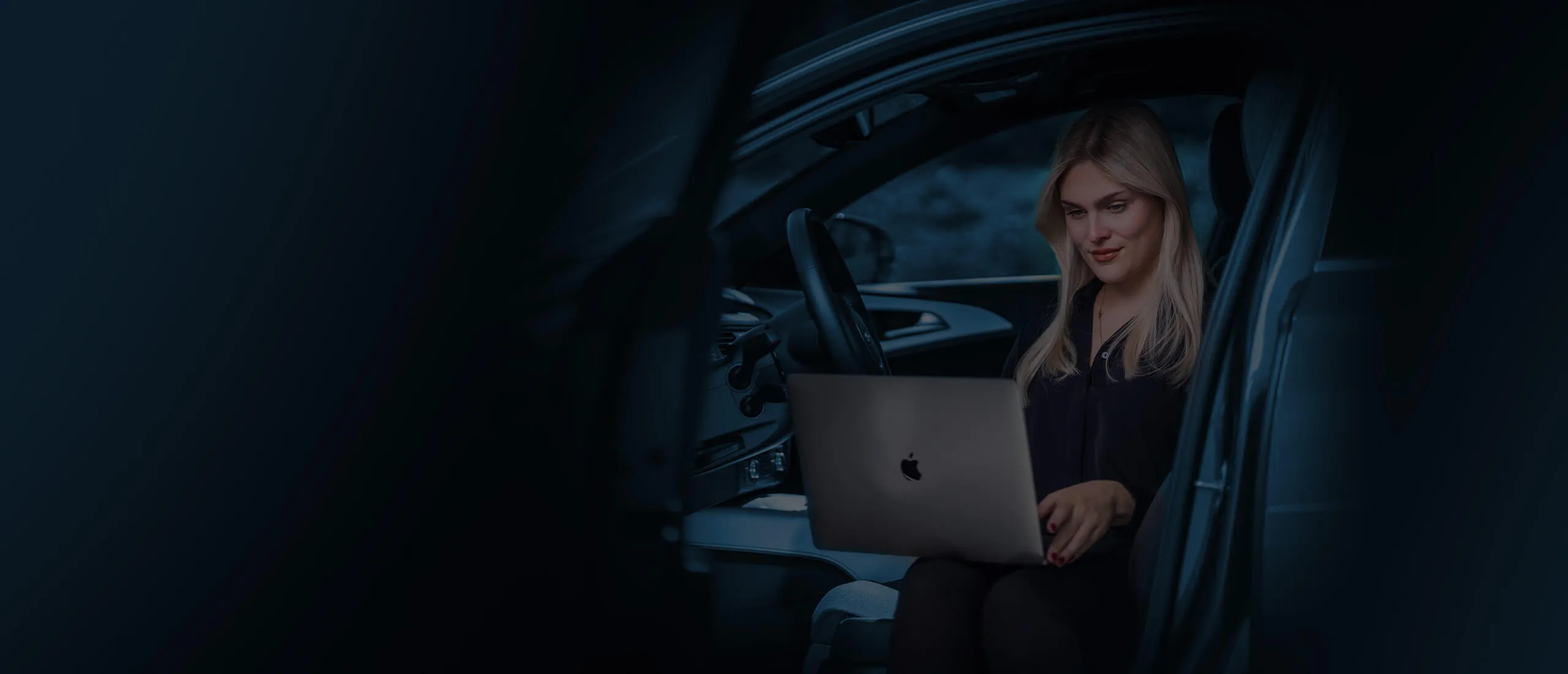 Geschäftsfrau arbeitet mit Laptop auf dem Beifahrersitz eines Autos
