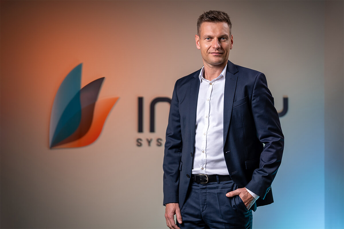 Porträt vor dem Firmenlogo von Inway Systems an der Bürowand